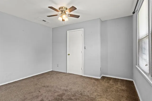 an empty room with windows and chandelier fan