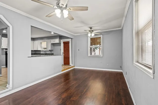 an empty room with wooden floor chandelier fan and windows