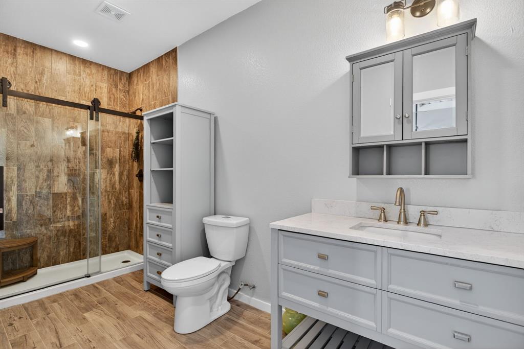 990 Doss Road Millsap, TX 76066 - Photo 28 of 39 a bathroom with a toilet a sink and glass door