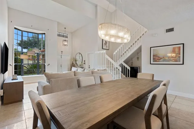 a living room with large couches table and a dining table with wooden floor