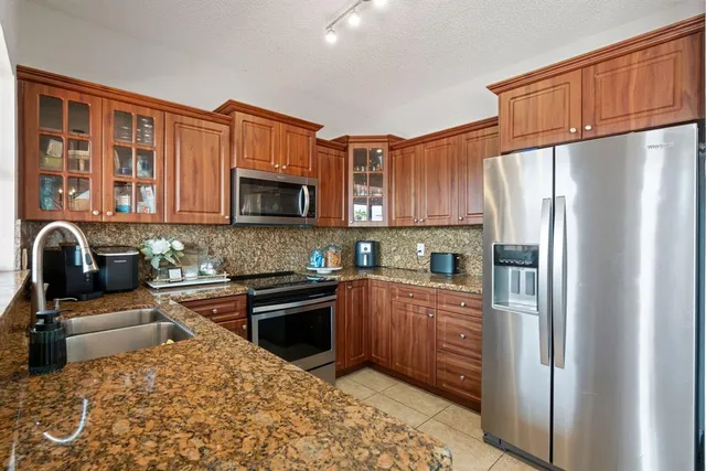 a kitchen with stainless steel appliances granite countertop a refrigerator stove top oven and sink