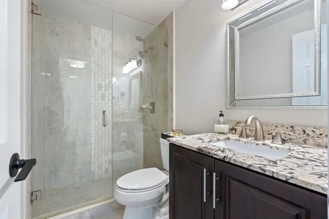 a bathroom with a granite countertop sink toilet and shower