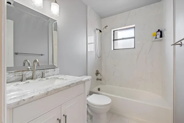 a bathroom with a granite countertop sink a toilet and bathtub