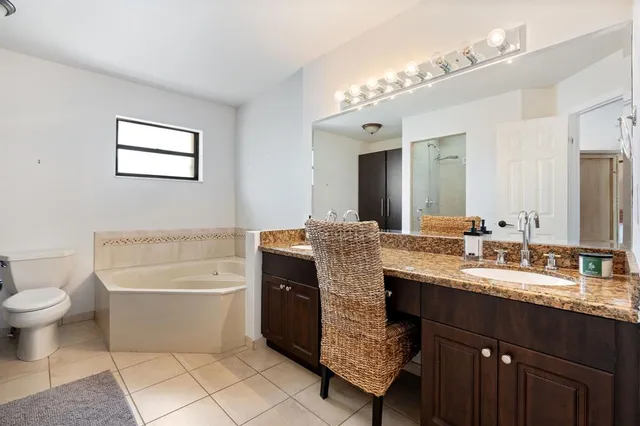 a bathroom with a granite countertop sink a toilet a mirror and bathtub