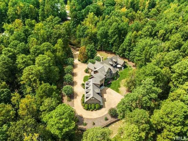 a view of a brick house with a big yard and large trees