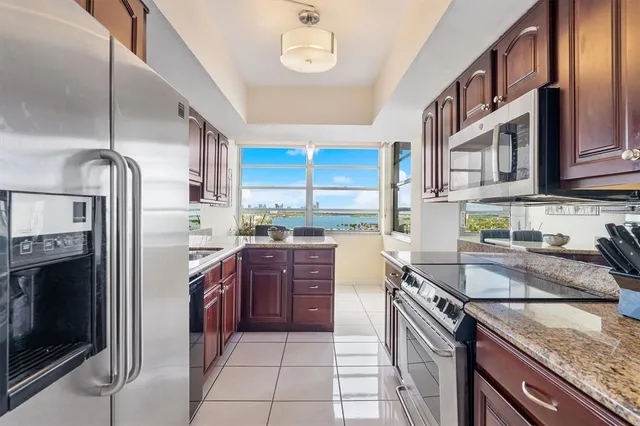 a kitchen with stainless steel appliances granite countertop a sink refrigerator and cabinets