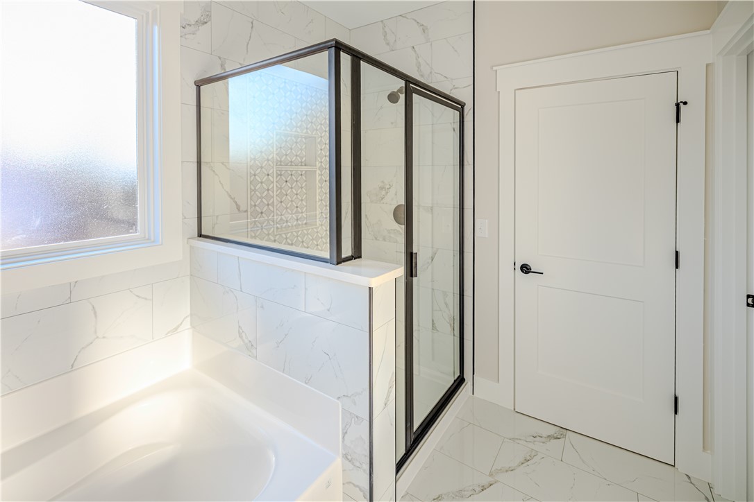 1409 Stonehurst Road Anderson, SC 29621 - Photo 30 of 37 This bright bathroom features a spacious tub and a modern walk-in shower with elegant tile work.