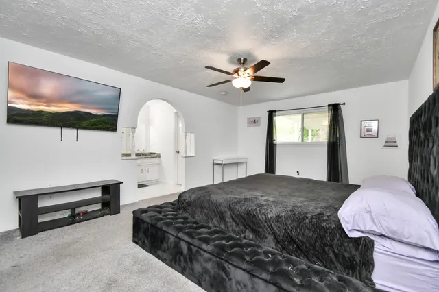 a spacious bedroom with a bed and a flat screen tv