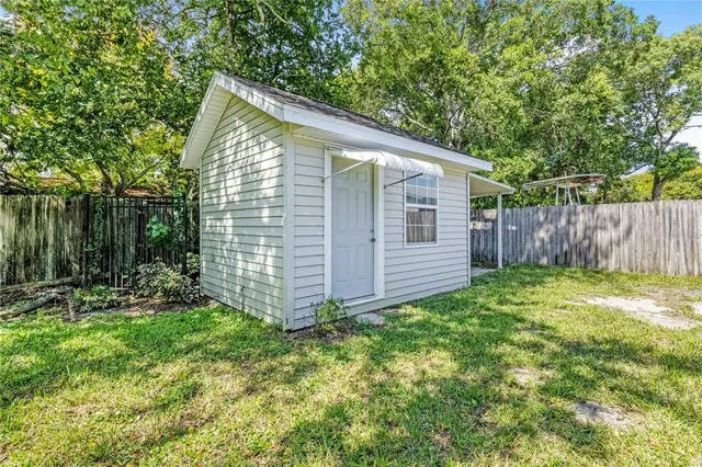 a view of a backyard with plants and large tree