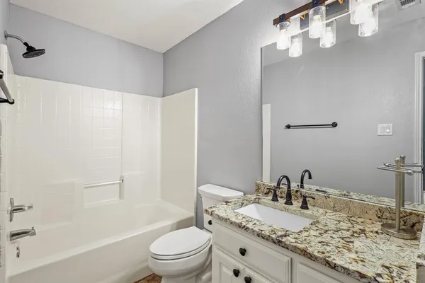 a bathroom with a granite countertop sink a toilet and shower