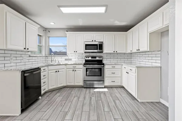 a kitchen with white cabinets stainless steel appliances and wooden floor