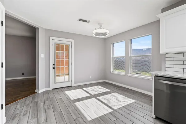 an empty room with wooden floor and windows