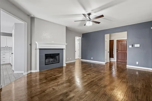 a view of an empty room with wooden floor fireplace and a window