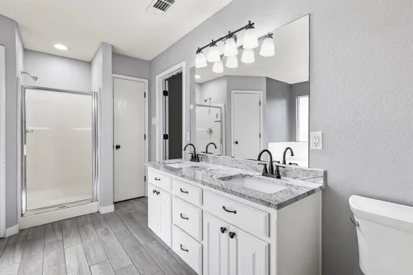 a bathroom with a granite countertop sink a mirror and a shower