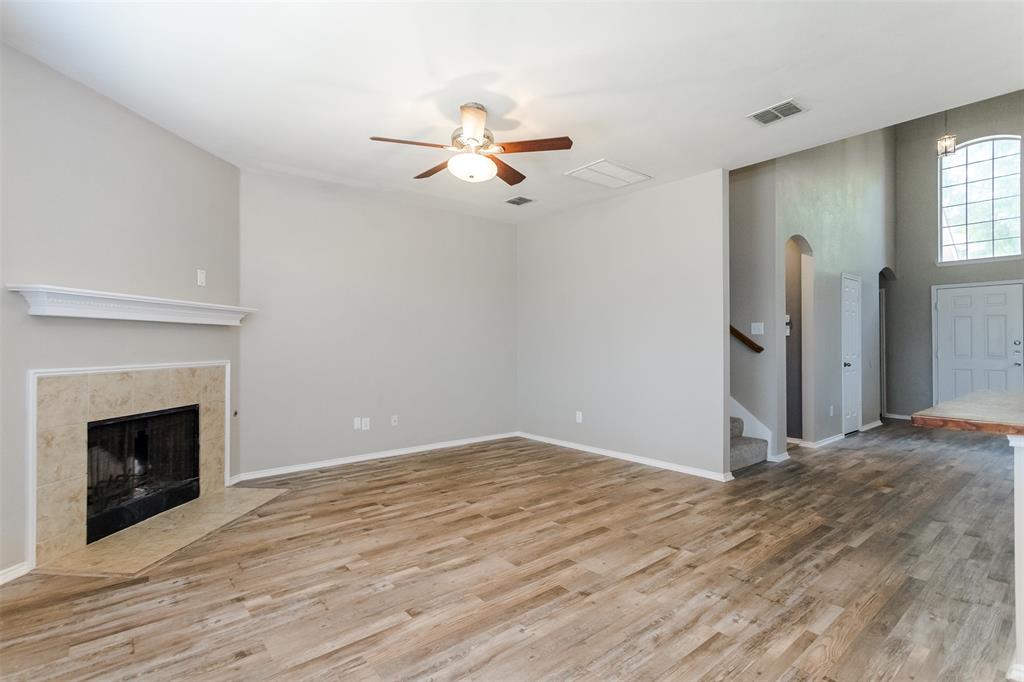 203 Arabian Road Waxahachie, TX 75165 - Photo 6 of 24 Spacious living area featuring wood-finish flooring, a tiled fireplace with a mantel, and a ceiling fan