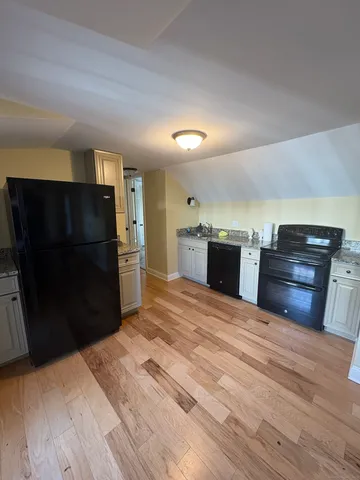 a kitchen with granite countertop a refrigerator and a stove top oven