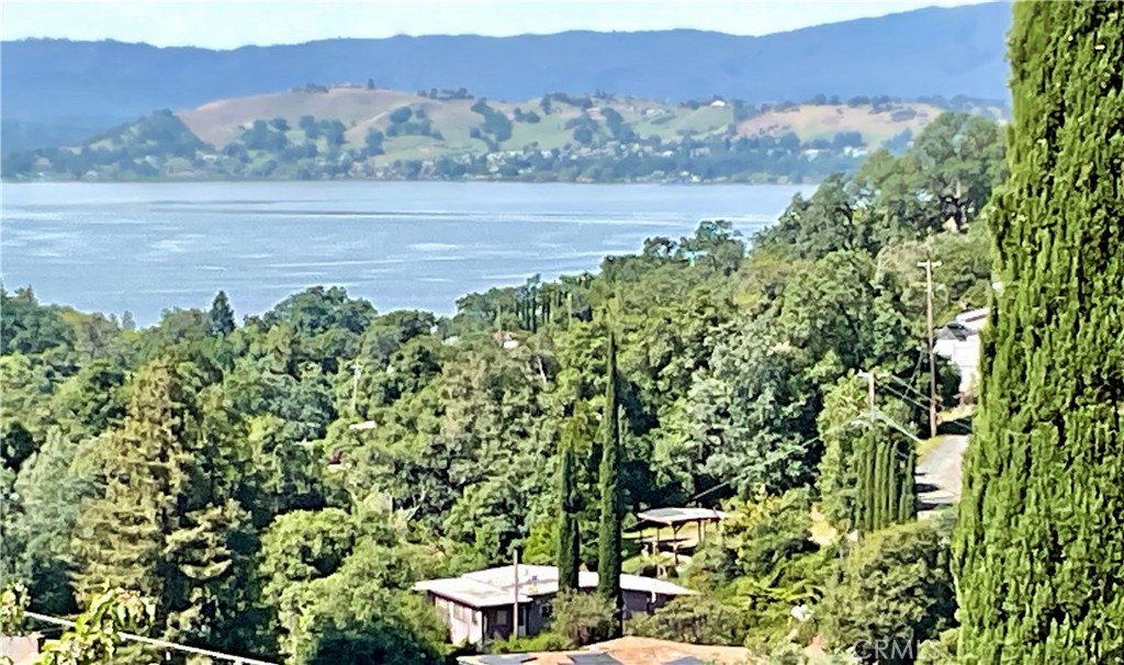 Aerial perspective of the full 4-lot estate (7252–7282 Marin St) featuring the existing home, carport, and immense privacy. This rare vantage point highlights the proximity to Clearlake and the potential for expansive panoramic views with selective clearing.