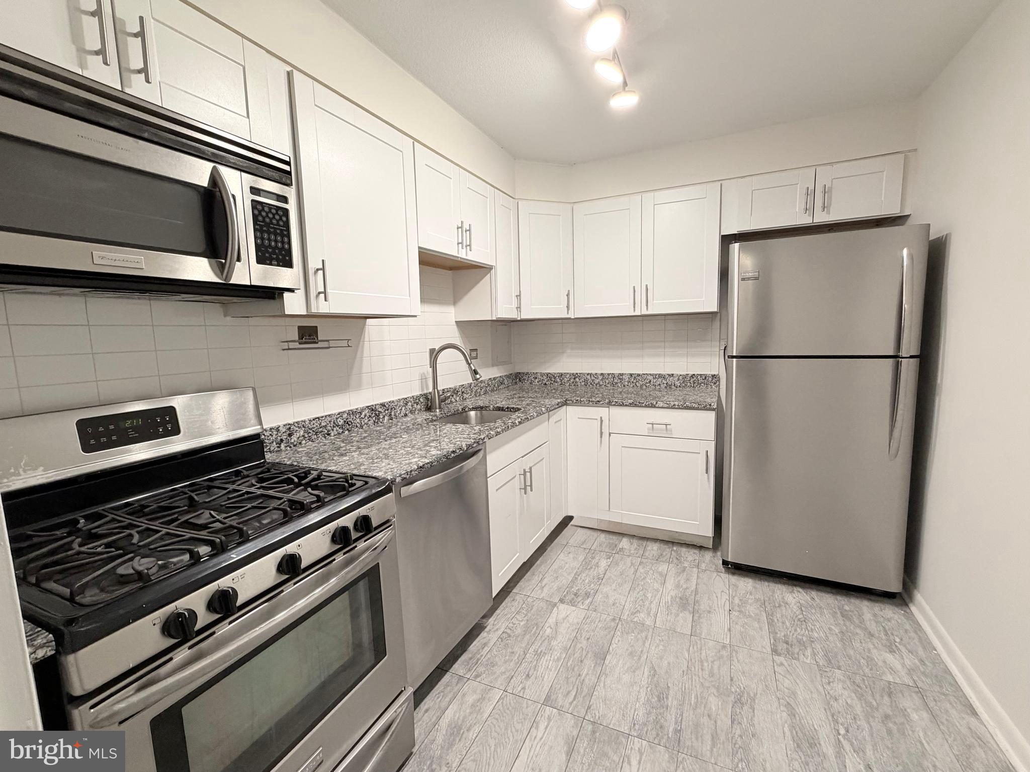 700 7th Street Southwest, Unit 406 Washington, DC 20024 - Photo 18 of 50 a kitchen with stainless steel appliances granite countertop a stove top oven a refrigerator a sink and white cabinets