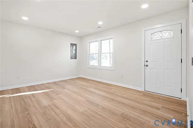 an empty room with wooden floor and windows