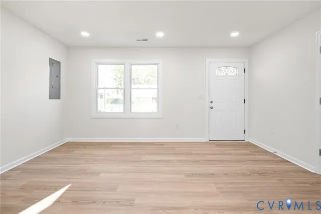 a view of an empty room with wooden floor and a window