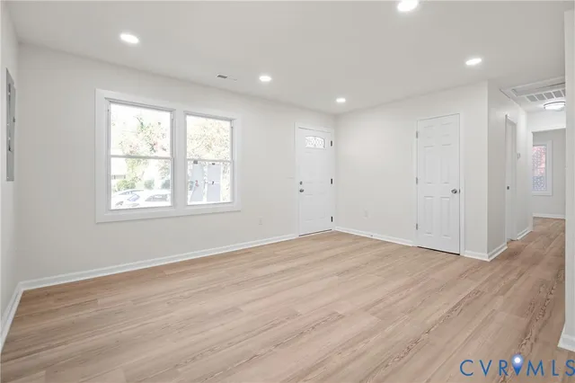 an empty room with wooden floor and windows
