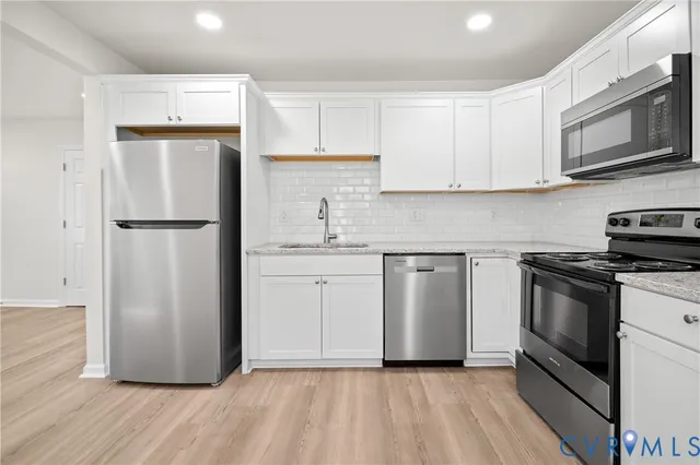 a kitchen with white cabinets stainless steel appliances and a refrigerator