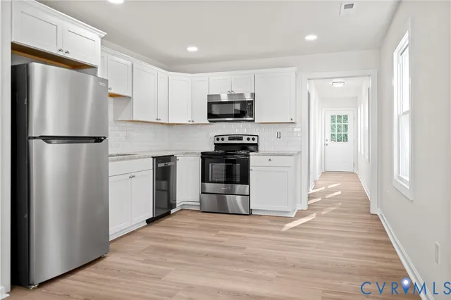 a kitchen with a refrigerator a stove top oven and cabinets
