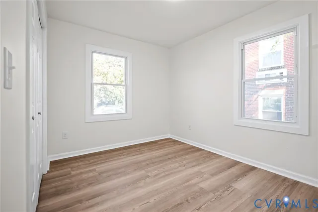 an empty room with wooden floor and windows