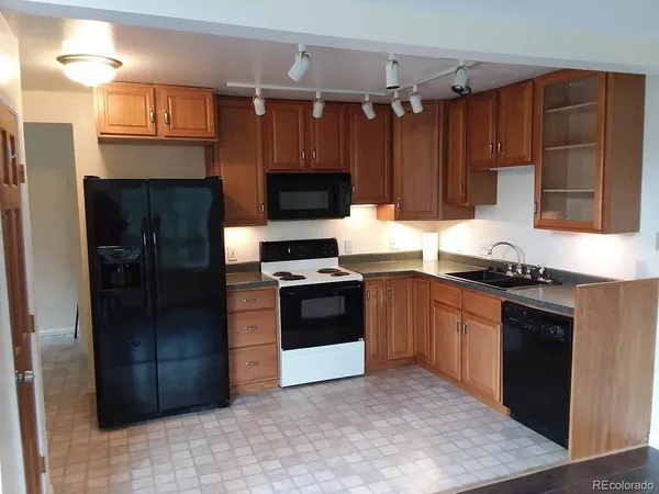 a kitchen with granite countertop a refrigerator and a stove top oven