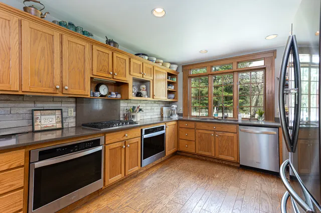 a kitchen with stainless steel appliances granite countertop hardwood floor sink stove and wooden cabinets