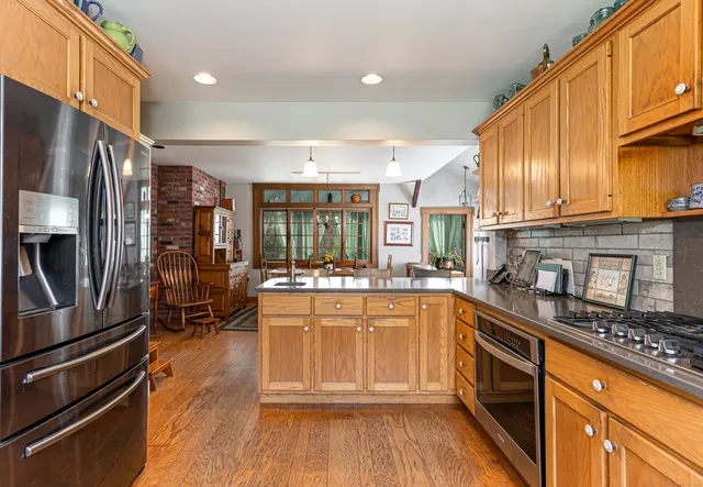 a kitchen with stainless steel appliances granite countertop a refrigerator a stove and a wooden floors