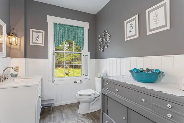 a bathroom with a granite countertop toilet a sink and a window