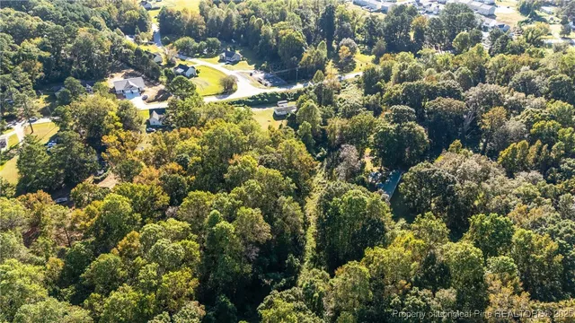 an aerial view of residential house with parking space and covered by trees