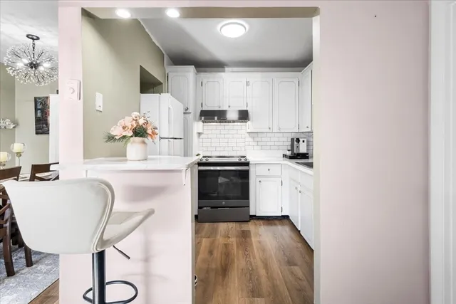 a kitchen with granite countertop white cabinets and stainless steel appliances