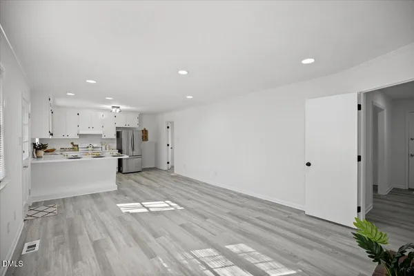 a large white kitchen with a sink a window and stainless steel appliances