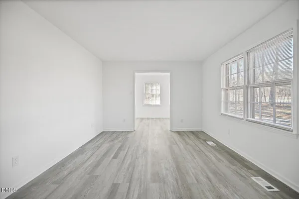 a large white kitchen with wooden floors and view living room