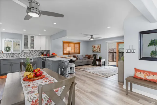 a kitchen with stainless steel appliances kitchen island granite countertop a dining table chairs and refrigerator