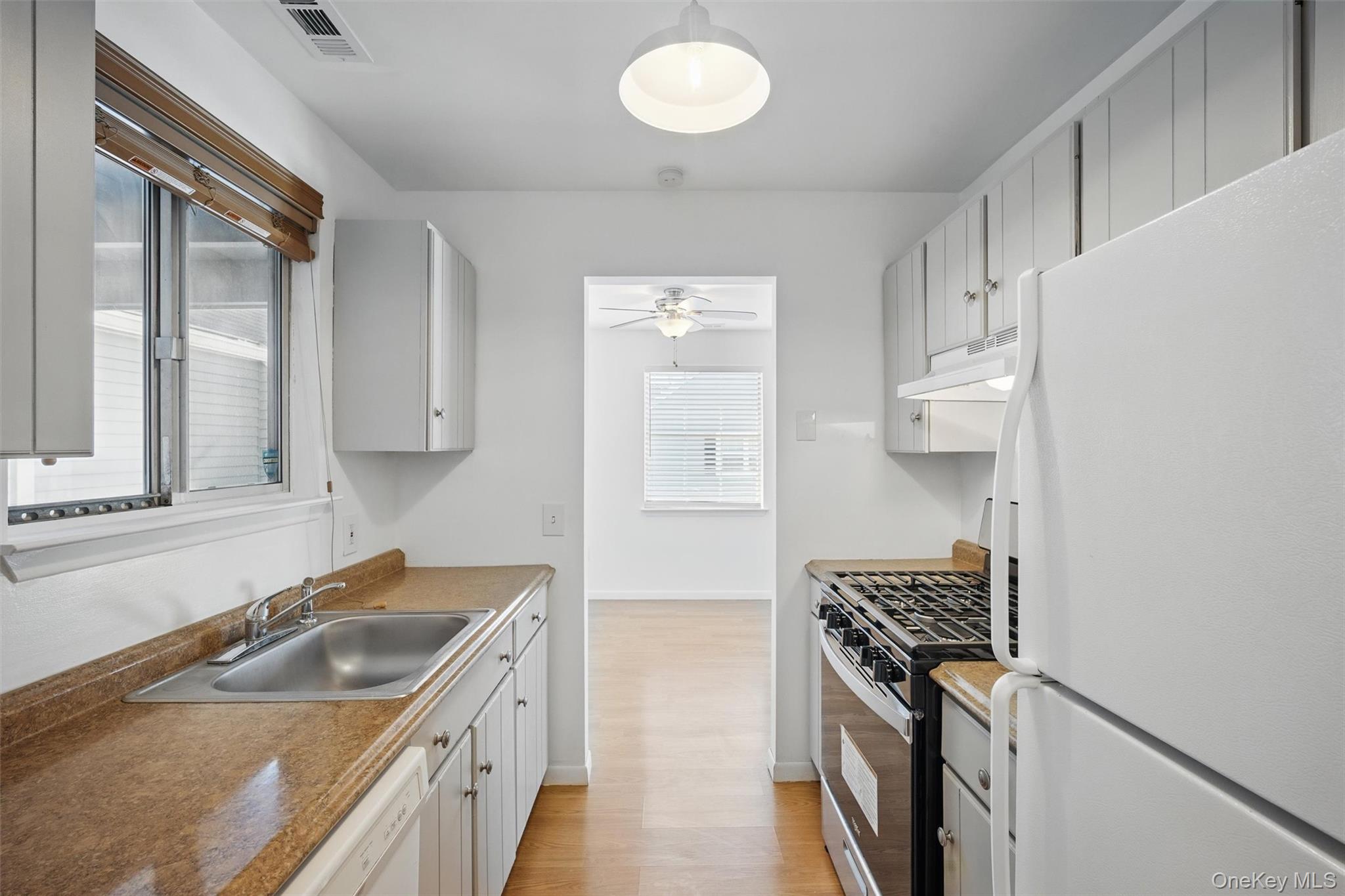 201 Commons Way, Unit E Fishkill, NY 12524 - Photo 13 of 30 Kitchen featuring white appliances, light wood-type flooring, under cabinet range hood, a ceiling fan, and white cabinets