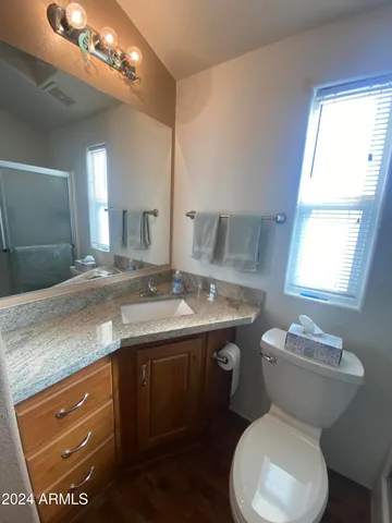 a bathroom with a granite countertop toilet sink and mirror