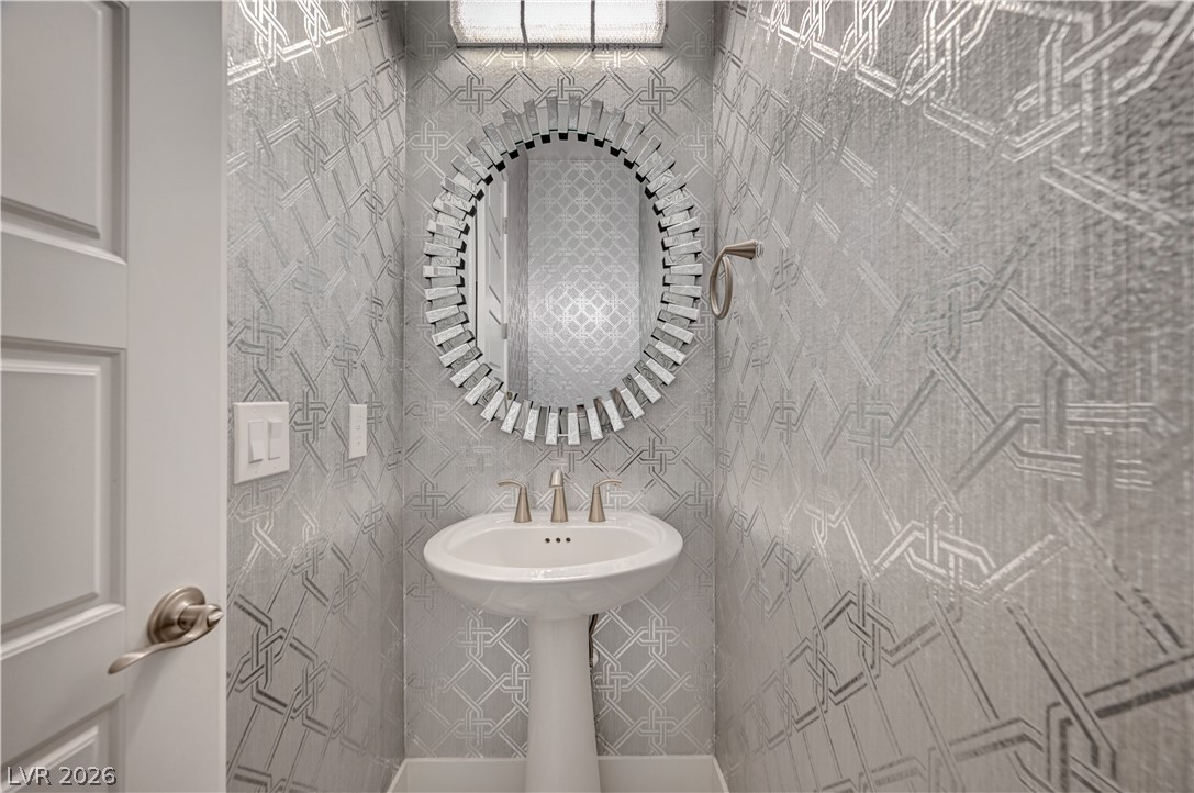 3943 Reyes Avenue Las Vegas, NV 89141 - Photo 44 of 95 Elegant powder room featuring a sleek pedestal sink and distinctive patterned wall covering.