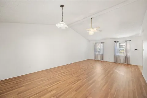 a view of empty room with wooden floor and ceiling fan