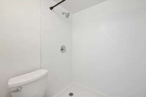 a white toilet sitting next to a shower