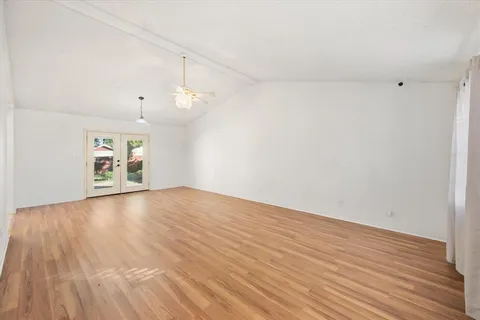 a view of an empty room with window and wooden floor