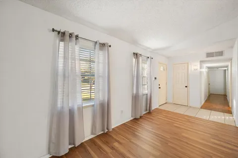 a view of empty room with wooden floor and fan