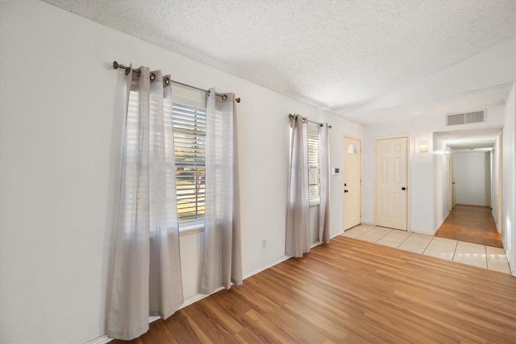 7308 Red Osier Road Dallas, TX 75249 - Photo 9 of 27 a view of empty room with wooden floor and fan