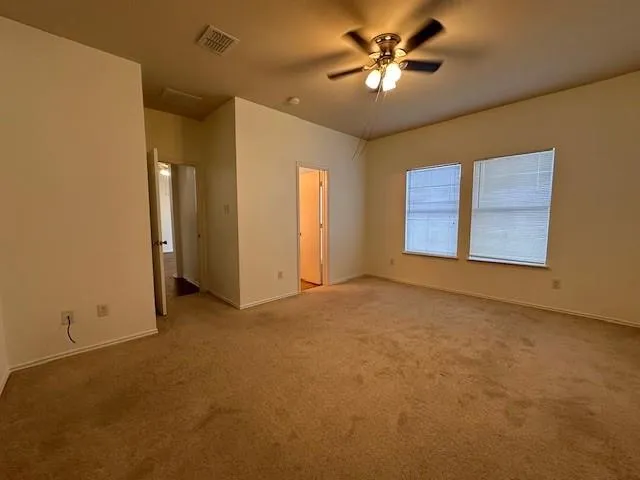 an empty room with windows and fan