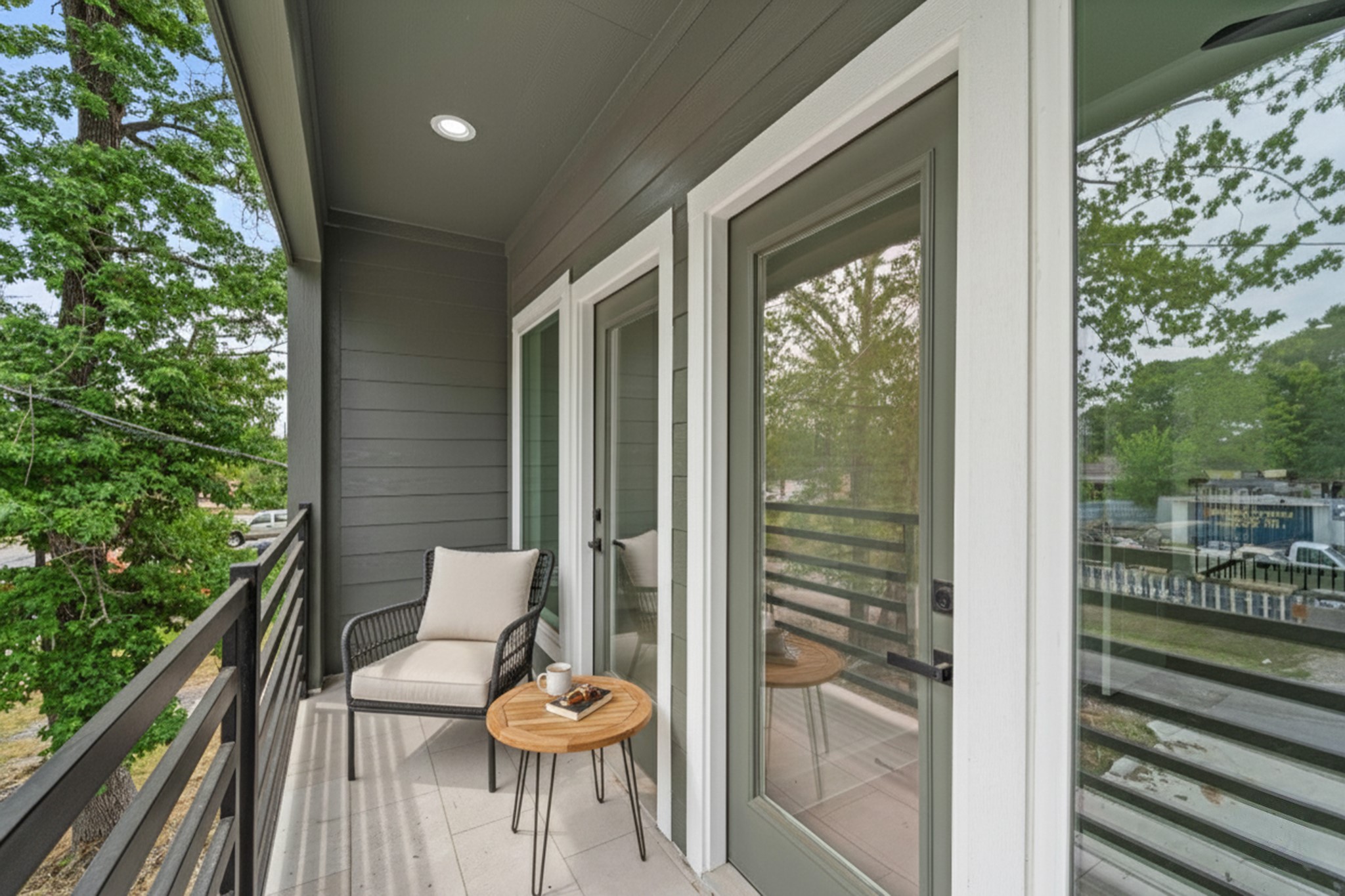 7709 Willow Street Houston, TX 77088 - Photo 12 of 15 This covered upper-level balcony features dark gray horizontal siding, a light-colored tiled floor, and a black horizontal railing.