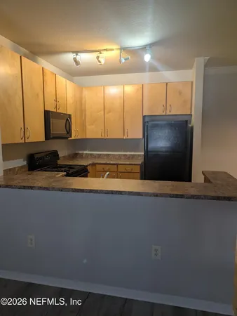 a view of a large kitchen with stainless steel appliances wooden floor and a large window