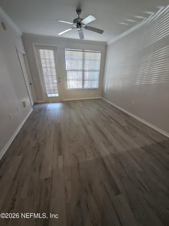 an empty room with wooden floor and windows