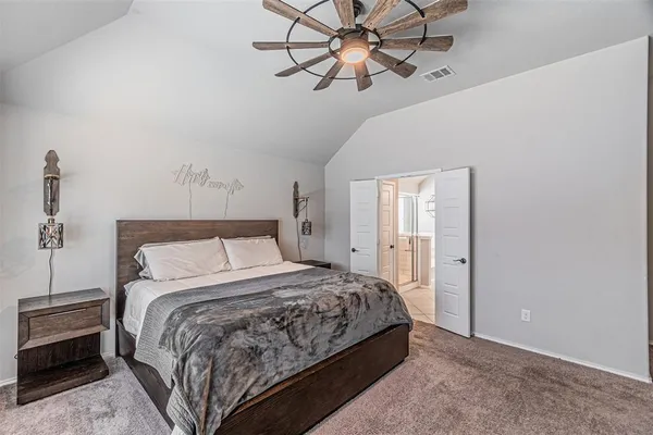 a spacious bedroom with a bed a chandelier and a large window